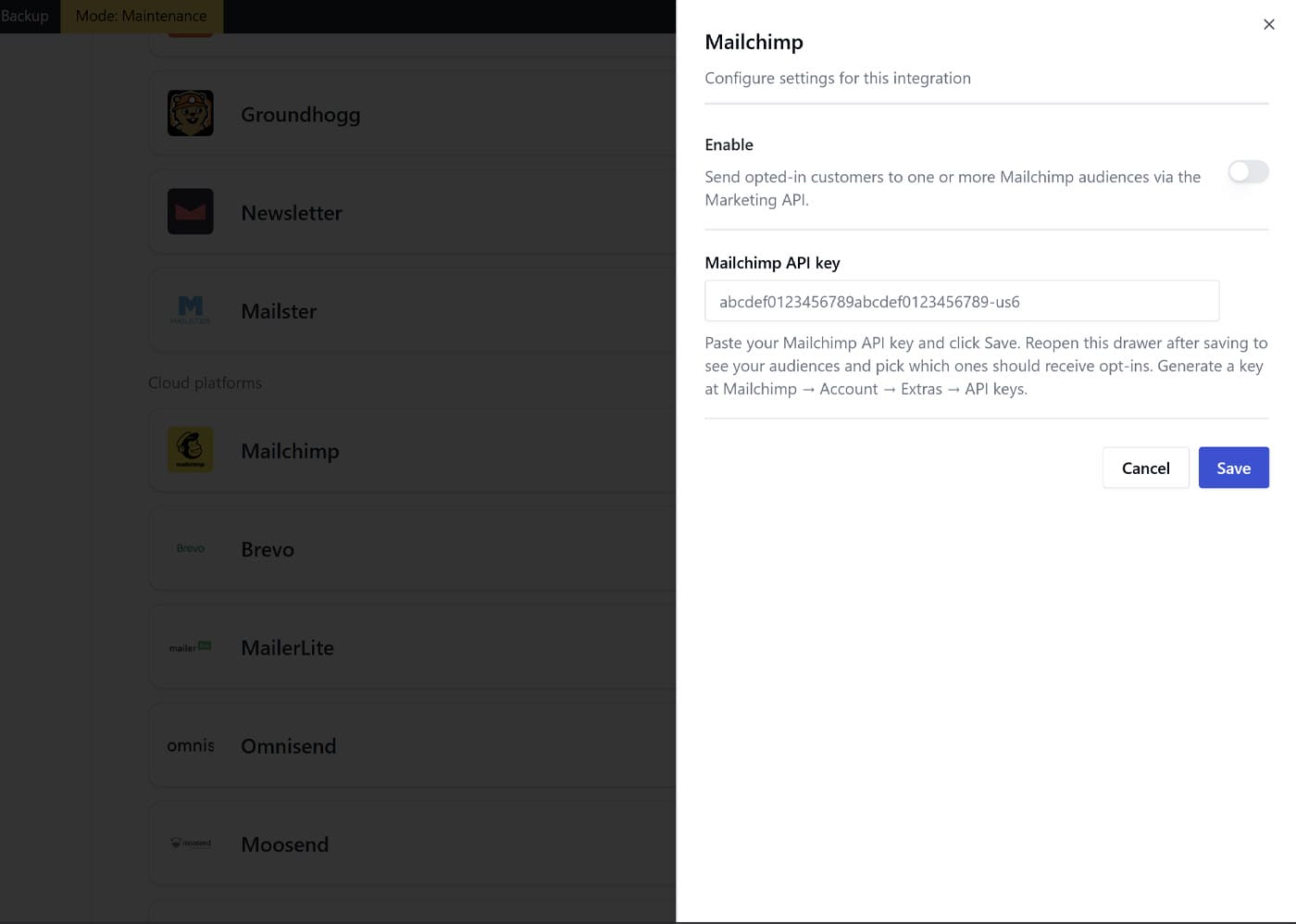 A white pop-up window titled "Mailchimp" overlays a dark interface. The form includes a toggle to enable Mailchimp, a field labeled "Mailchimp API key" with a sample key, and "Cancel" and blue "Save" buttons at the bottom right.